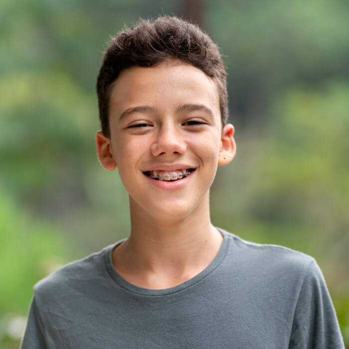 Teen boy with braces smiling outside in summer